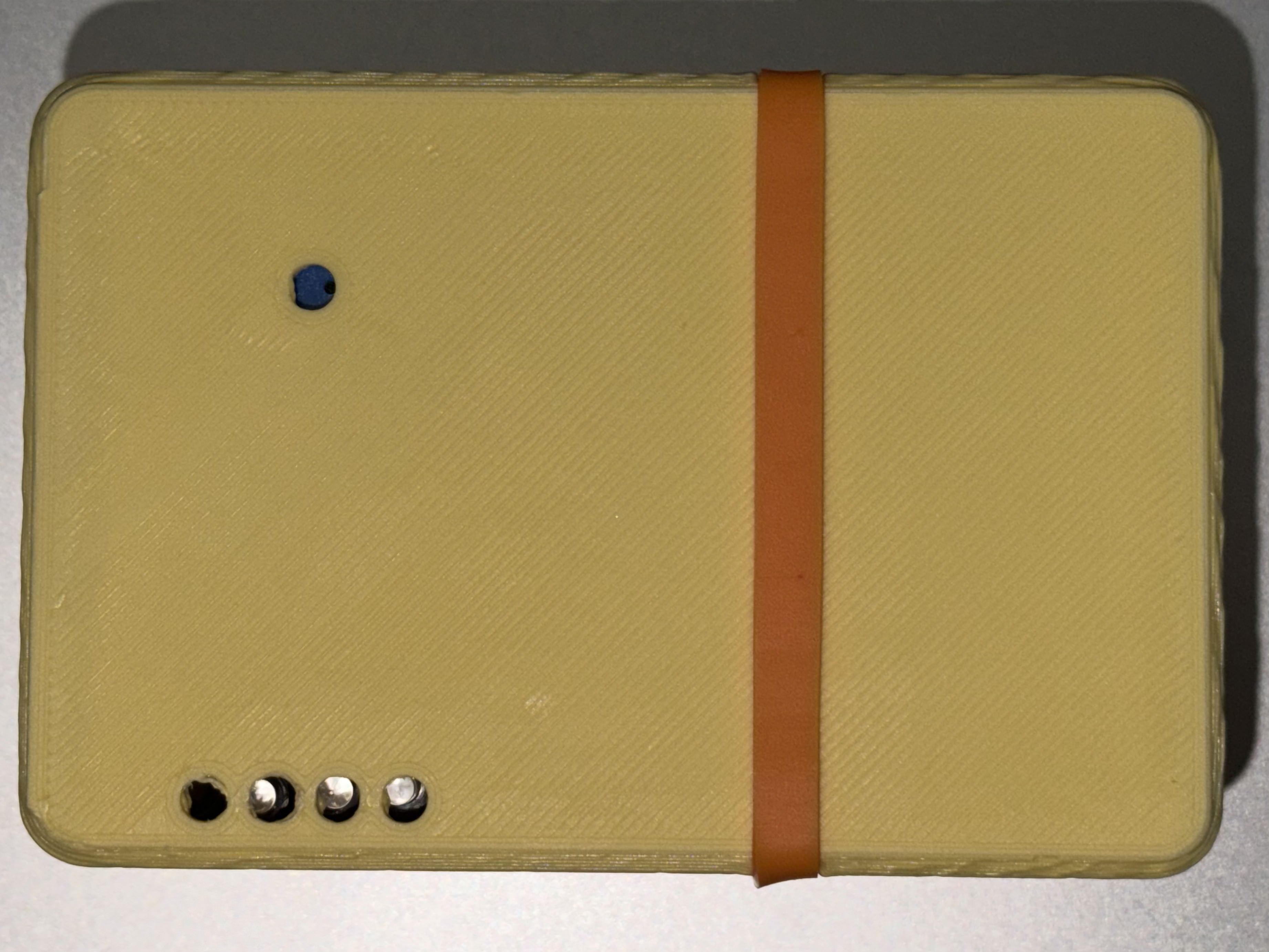 Top view of yellow PLA case closed, LED holes and rubber band groove visible