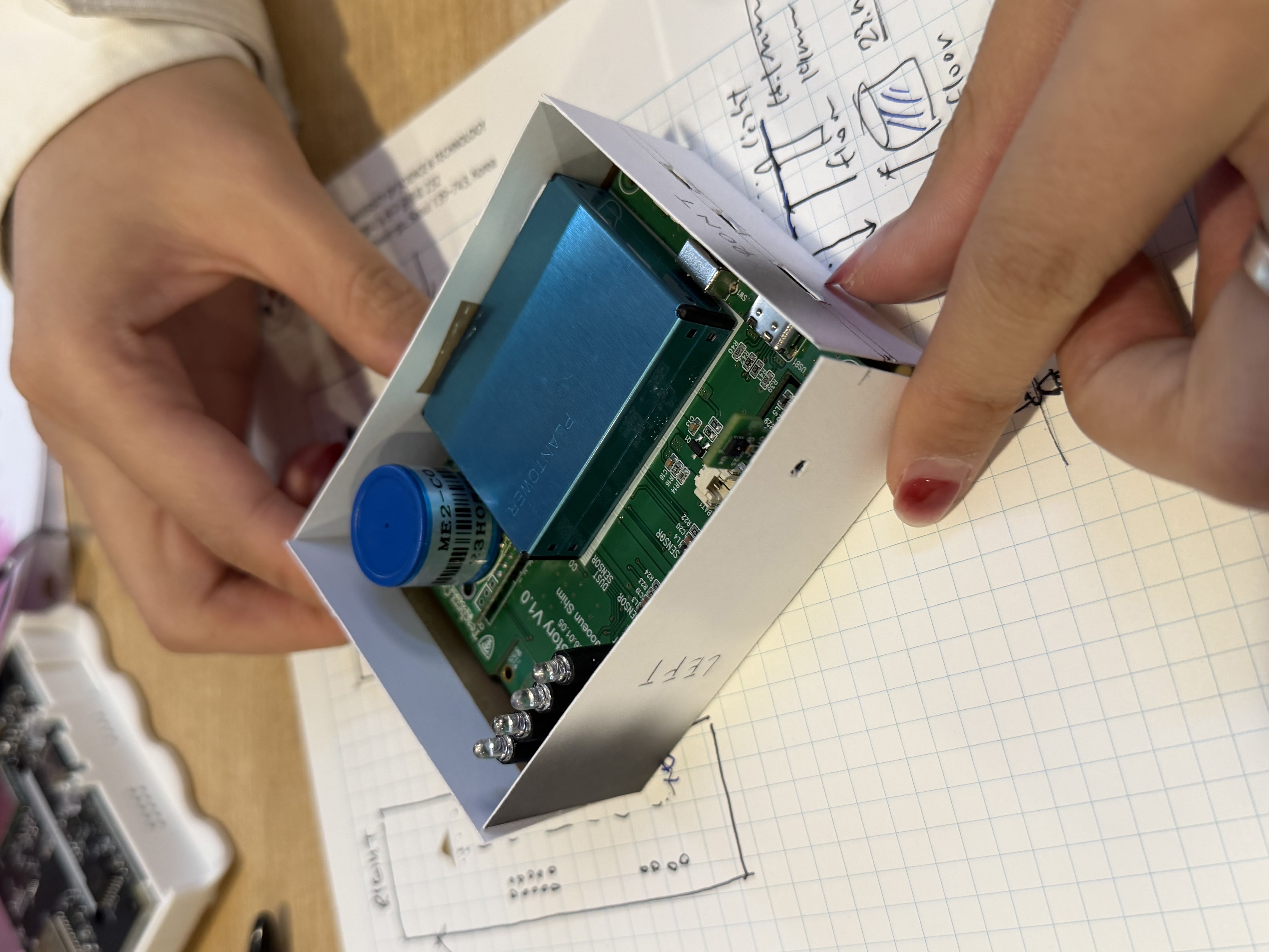 Paper case holding actual PCB board, graph paper with dimension sketches